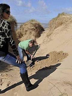 Bizarre femdom scenario where guy digs the hole in the ground and the girl is burying him leaving just the head above