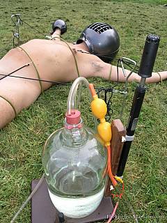 Blonde dominatrix is out in the field: spread-eagled poor male on the grass and doing horrible things to his cock and balls